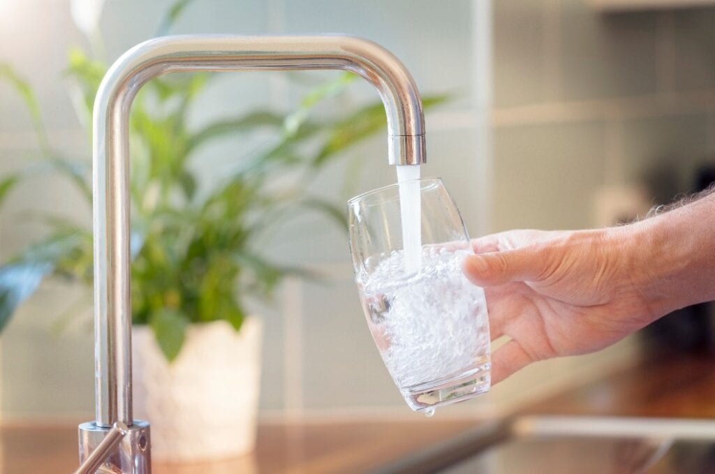 Filling up a glass with drinking water from kitchen tap