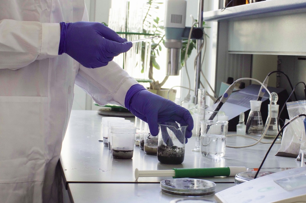 Die Hände des Wissenschaftlers beim Mischen von Bodenproben