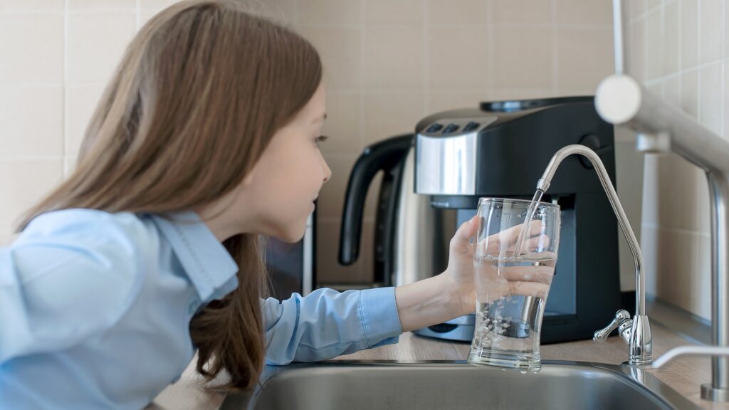 Kind öffnet Wasserhahn. Küchenwasserhahn. Glas mit sauberem Wasser. Frisches Getränk einschenken. Flüssigkeitszufuhr. Gesunder Lebensstil. Konzept zur Überprüfung der Wasserqualität. Welttag der Wasserüberwachung. Problem der Umweltverschmutzung
