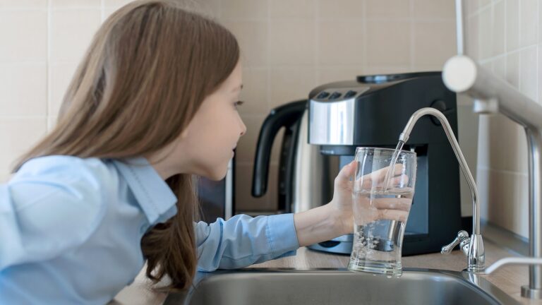 Kind öffnet Wasserhahn. Küchenwasserhahn. Glas mit sauberem Wasser. Frisches Getränk einschenken. Flüssigkeitszufuhr. Gesunder Lebensstil. Konzept zur Überprüfung der Wasserqualität. Welttag der Wasserüberwachung. Problem der Umweltverschmutzung