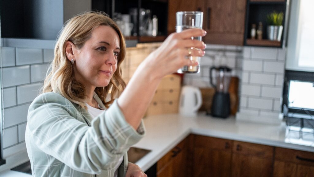 Frau, die in einer modernen Küche die Wasserqualität überprüft